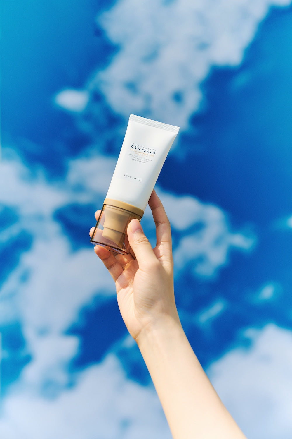 SKIN1004 Air-Fit Suncream Light placed in a beach bag alongside sunglasses